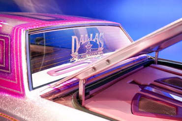 a light pink lowrider car with "Dallas Lowriders" on the back window